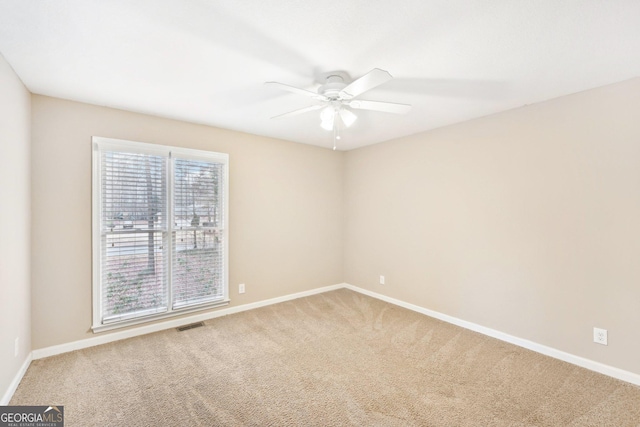 spare room featuring carpet floors, ceiling fan, visible vents, and baseboards