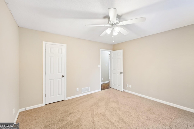 unfurnished bedroom featuring baseboards, visible vents, ceiling fan, and carpet flooring