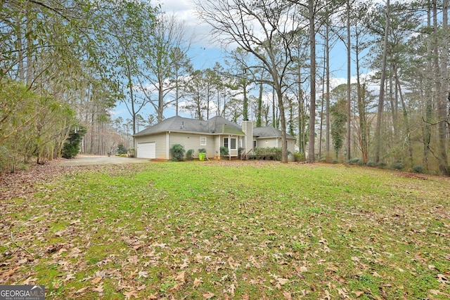 exterior space with a front yard, a chimney, and an attached garage