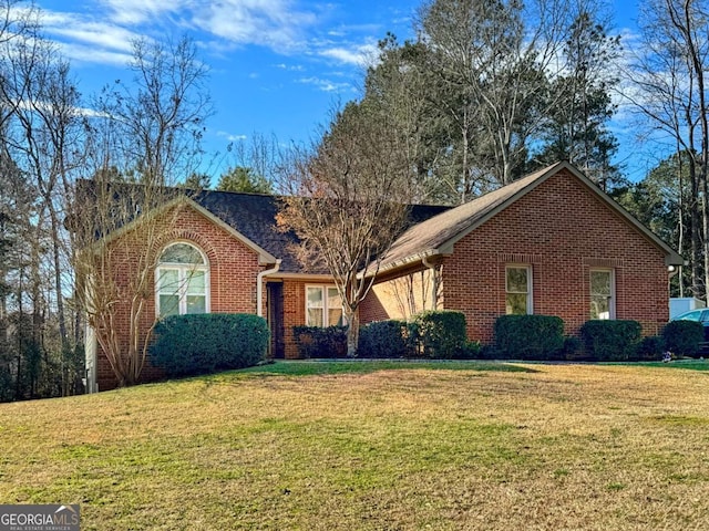 ranch-style house with a front yard, brick siding, and roof with shingles