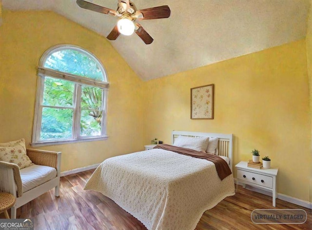 bedroom with lofted ceiling, multiple windows, baseboards, and wood finished floors