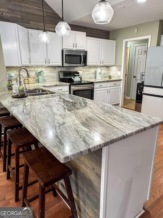 kitchen featuring a peninsula, light wood finished floors, appliances with stainless steel finishes, and white cabinets