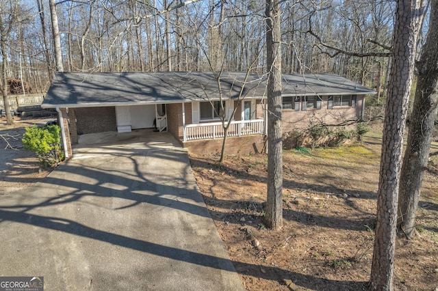 single story home with covered porch, driveway, and brick siding