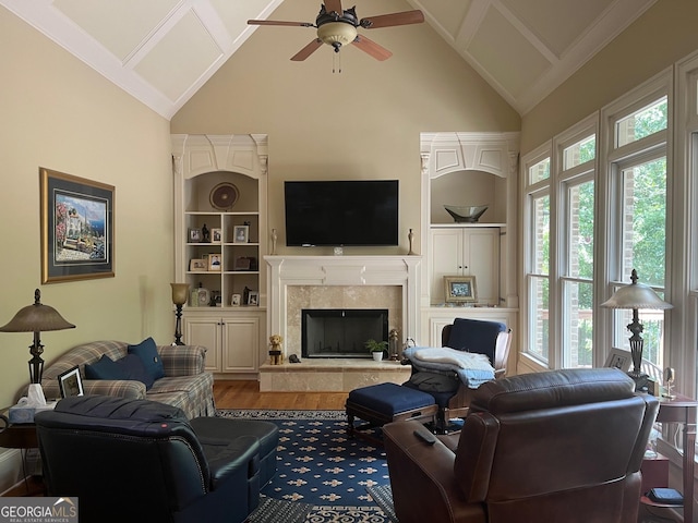 living area with ceiling fan, high vaulted ceiling, wood finished floors, a high end fireplace, and built in features