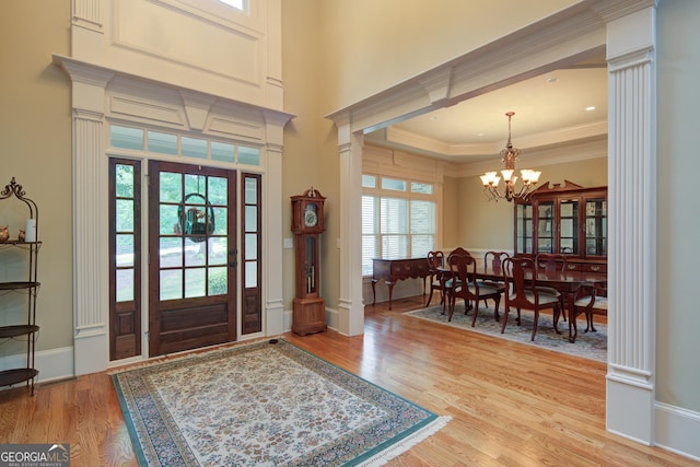 8440 Woodland Brooke Trl, Cumming, GA 30028 - entryway featuring light wood-type flooring, a chandelier, crown molding, and ornate columns