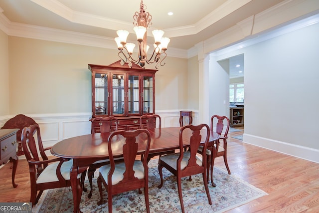 8440 Woodland Brooke Trl, Cumming, GA 30028 - dining space with light wood finished floors, a raised ceiling, a chandelier, wainscoting, and crown molding