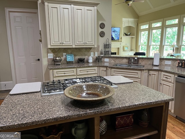 kitchen featuring dark stone counters, a center island, stainless steel appliances, open shelves, and a sink