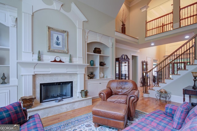 8440 Woodland Brooke Trl, Cumming, GA 30028 - living room with wood finished floors, built in shelves, a high ceiling, stairs, and a premium fireplace