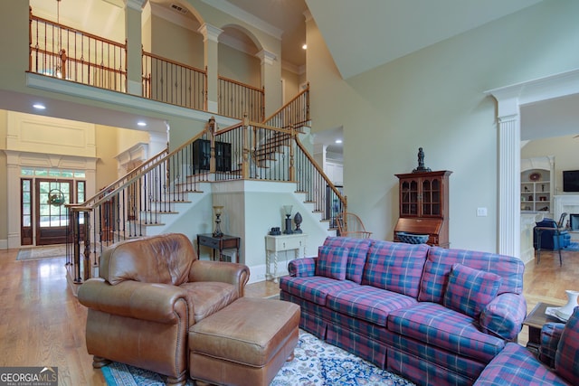 8440 Woodland Brooke Trl, Cumming, GA 30028 - living area with a high ceiling, decorative columns, stairs, wood finished floors, and baseboards
