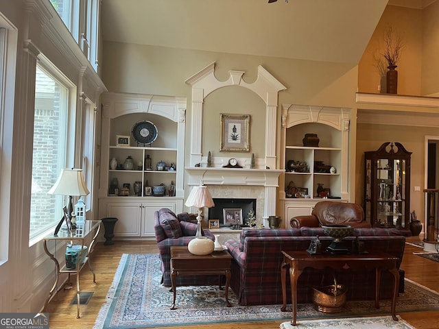 living area with a fireplace, plenty of natural light, wood finished floors, and built in features