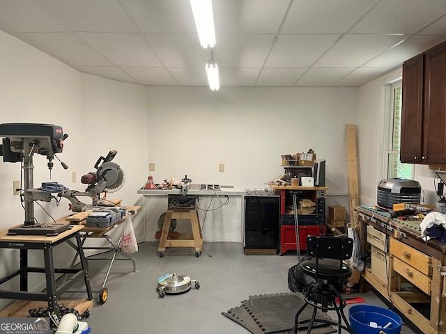 misc room featuring a paneled ceiling, concrete flooring, and a workshop area