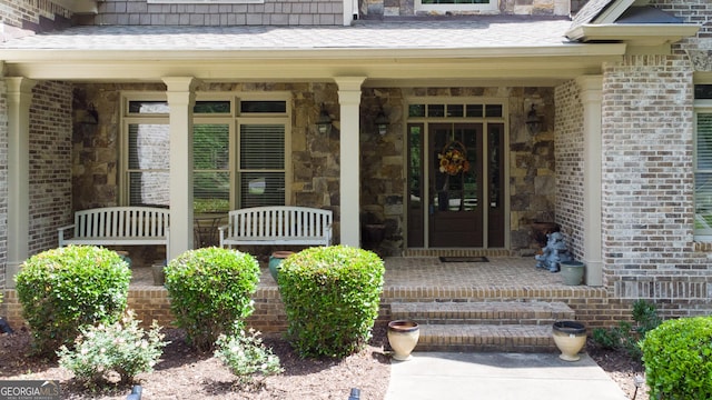 8440 Woodland Brooke Trl, Cumming, GA 30028 - property entrance with a porch, stone siding, and brick siding