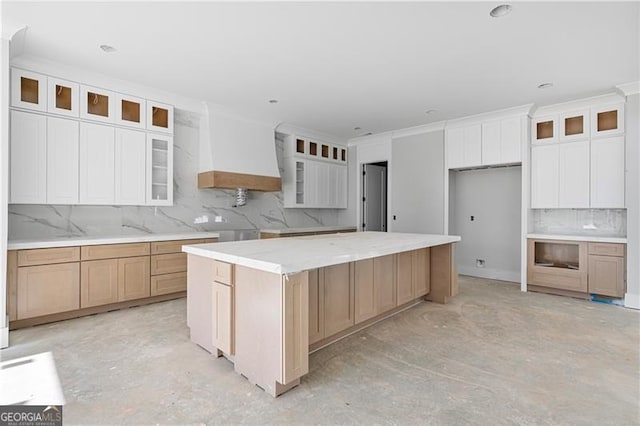 kitchen featuring a spacious island, white cabinetry, custom range hood, and glass insert cabinets