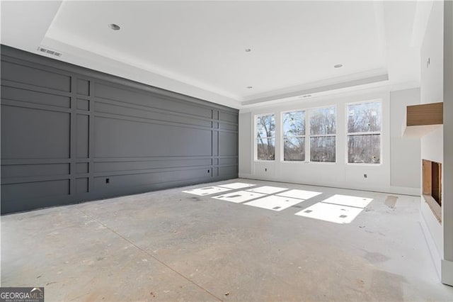 unfurnished living room with a raised ceiling, visible vents, and a decorative wall