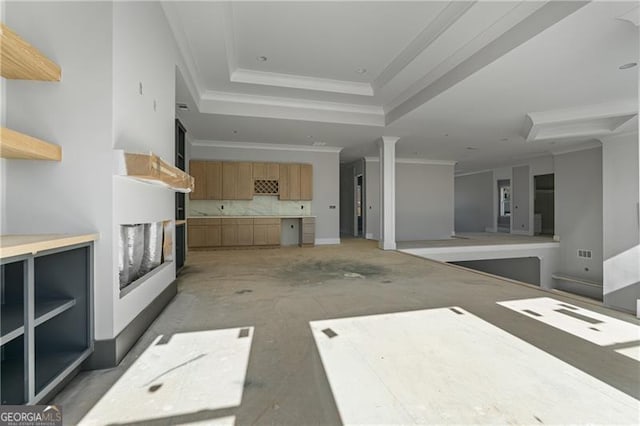 unfurnished living room with ornamental molding, a tray ceiling, and decorative columns