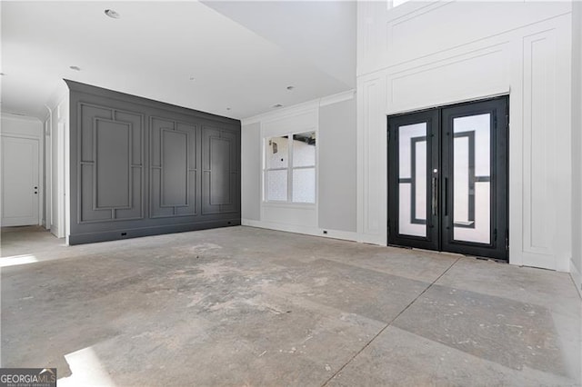 foyer entrance with crown molding, french doors, unfinished concrete flooring, and baseboards