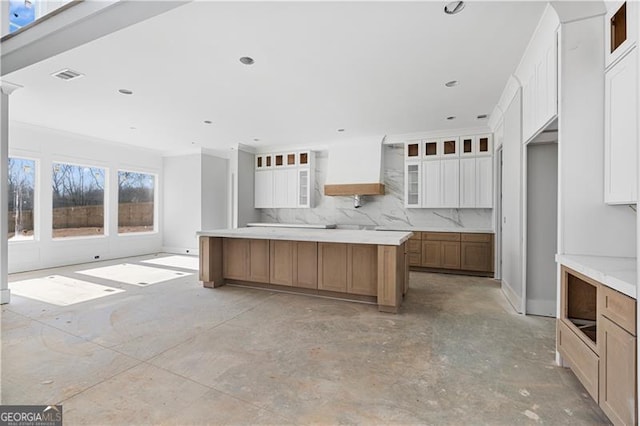 kitchen featuring a large island, custom exhaust hood, light countertops, glass insert cabinets, and white cabinets