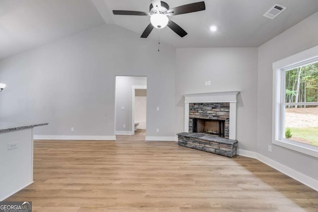 unfurnished living room with visible vents, baseboards, lofted ceiling, light wood-style flooring, and a fireplace