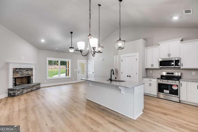 kitchen with white cabinets, an island with sink, stainless steel appliances, and open floor plan