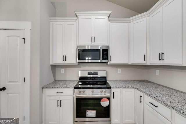 kitchen featuring lofted ceiling, appliances with stainless steel finishes, light stone countertops, and white cabinets