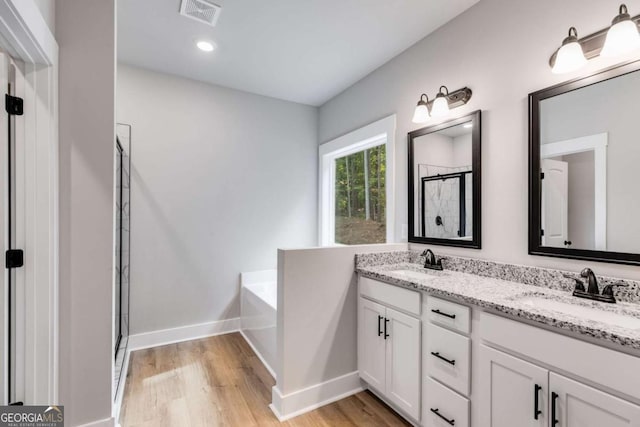 full bathroom featuring a bath, visible vents, a sink, and wood finished floors