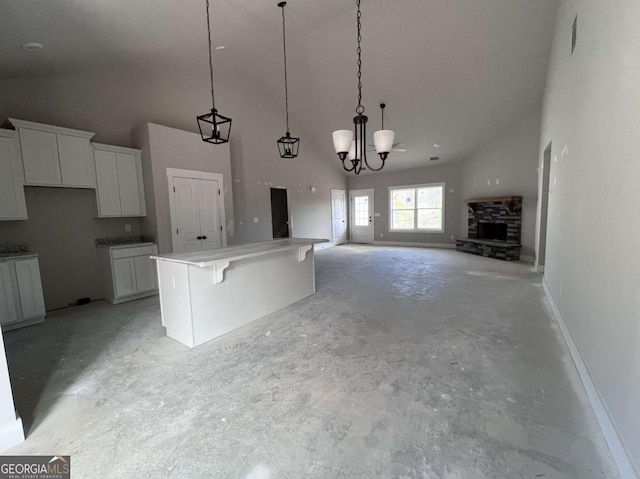 kitchen with white cabinets, a breakfast bar, open floor plan, decorative light fixtures, and a center island