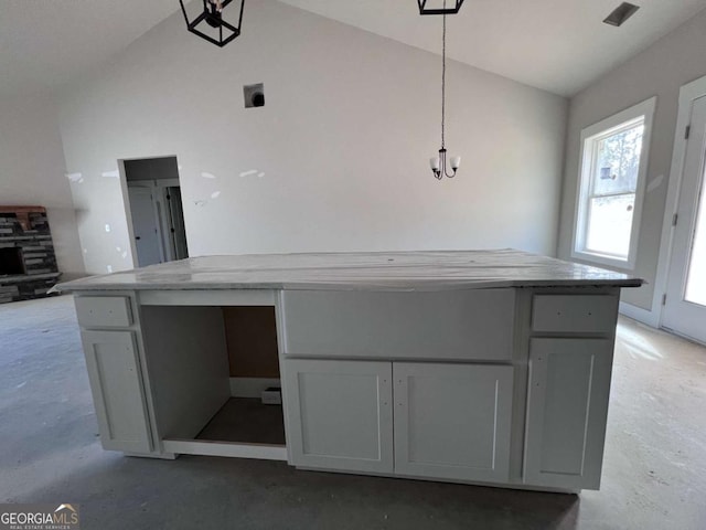 kitchen featuring high vaulted ceiling, concrete floors, light countertops, gray cabinets, and decorative light fixtures