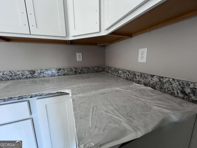 interior details featuring light stone counters and white cabinets