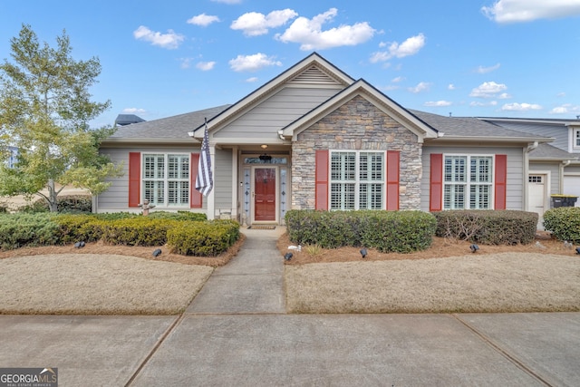 view of front of home with stone siding and roof with shingles