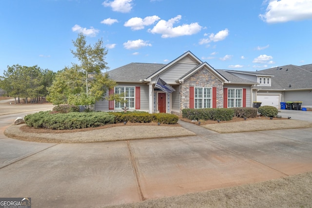 view of front of house with stone siding, an attached garage, and driveway