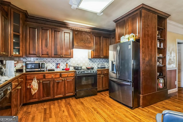 kitchen with light wood-type flooring, dark countertops, custom exhaust hood, and black appliances