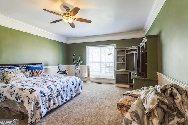 carpeted bedroom featuring ceiling fan, ornamental molding, and wainscoting