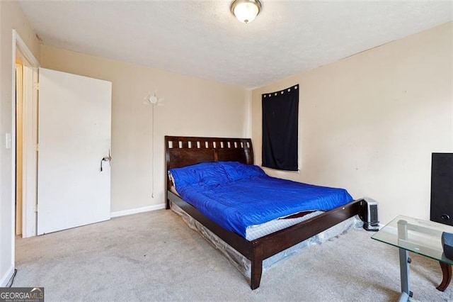 bedroom featuring light carpet, baseboards, and a textured ceiling