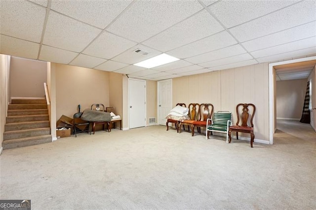 living area with carpet, visible vents, stairway, and a drop ceiling