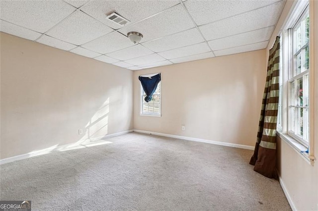 carpeted spare room featuring a paneled ceiling, visible vents, and baseboards