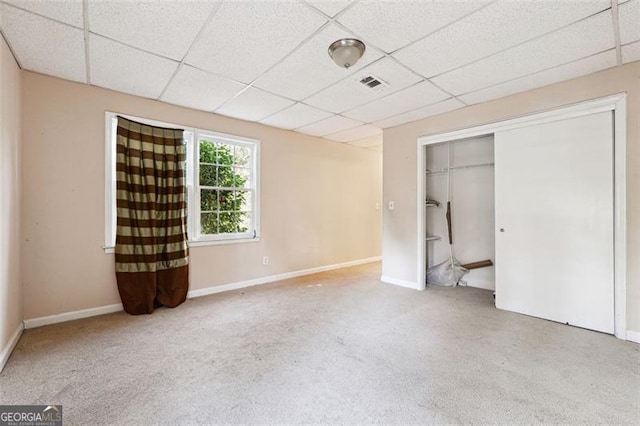 unfurnished bedroom with a paneled ceiling, a closet, visible vents, carpet flooring, and baseboards