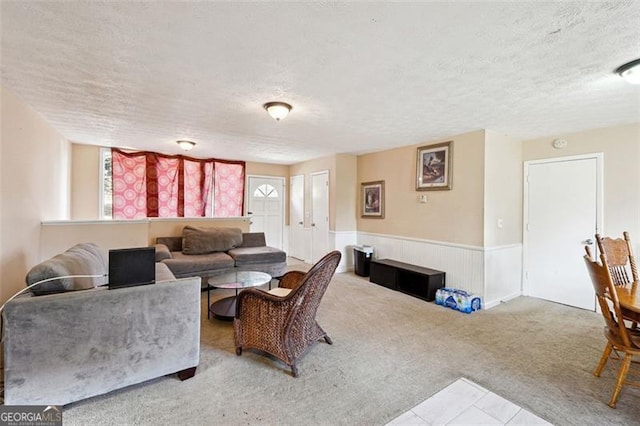 living room featuring a wainscoted wall, light carpet, and a textured ceiling