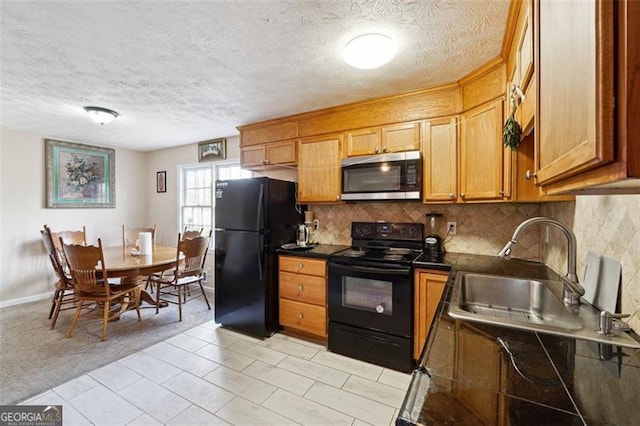 kitchen featuring brown cabinets, dark countertops, backsplash, a sink, and black appliances