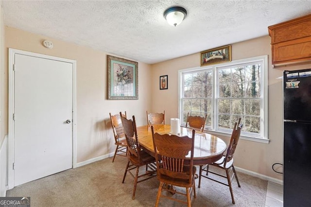 dining space featuring a textured ceiling, baseboards, a wealth of natural light, and light colored carpet