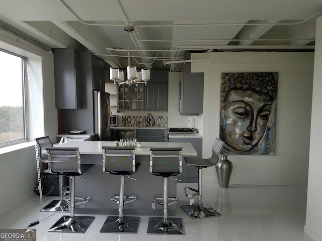 2479 Peachtree Rd NE Unit 1115, Atlanta, GA 30305 - kitchen with gray cabinets, glass insert cabinets, a peninsula, a kitchen bar, and appliances with stainless steel finishes