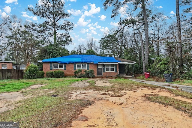 view of front of home featuring driveway, fence, and brick siding