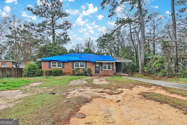 view of front of property featuring driveway, fence, and brick siding