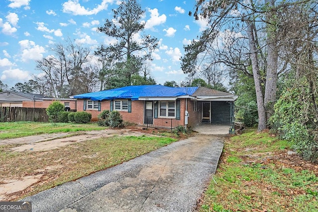 view of front facade featuring driveway, brick siding, a front lawn, and fence