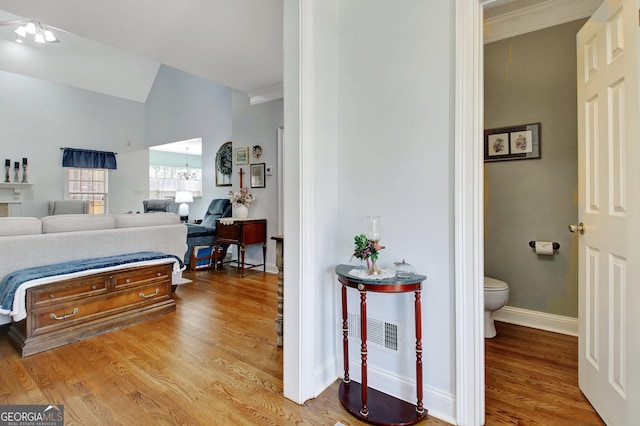 bedroom with ensuite bathroom, lofted ceiling, visible vents, baseboards, and light wood-style floors