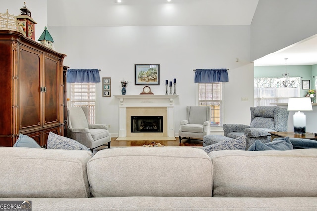 living room featuring a fireplace with raised hearth, wood finished floors, and a notable chandelier