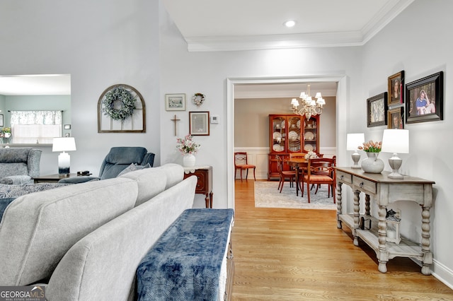 living area with ornamental molding, a chandelier, wainscoting, and light wood-style floors