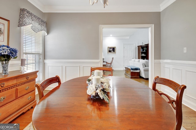 dining space featuring ornamental molding, a wainscoted wall, and wood finished floors