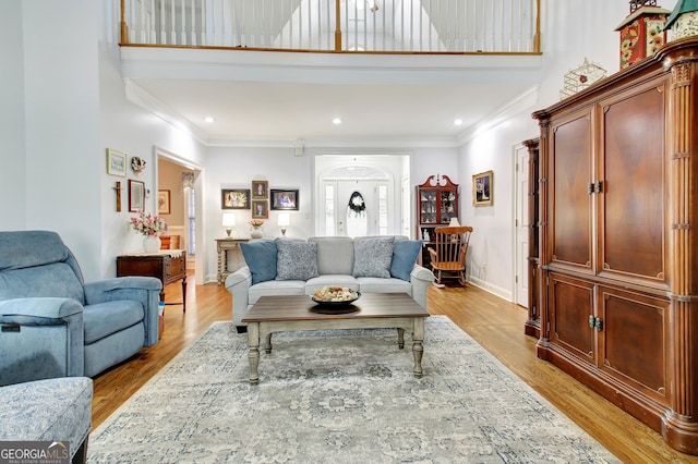 living room featuring recessed lighting, light wood-style flooring, a high ceiling, ornamental molding, and baseboards