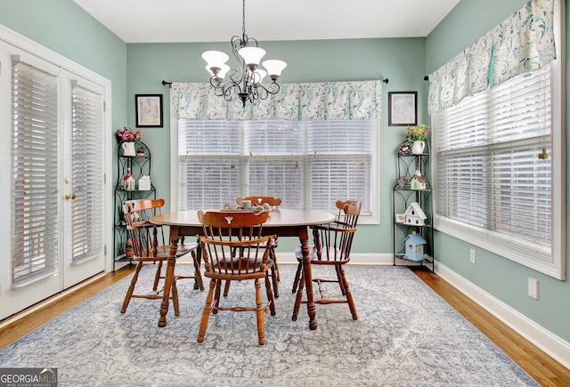 dining space featuring baseboards, wood finished floors, and a notable chandelier