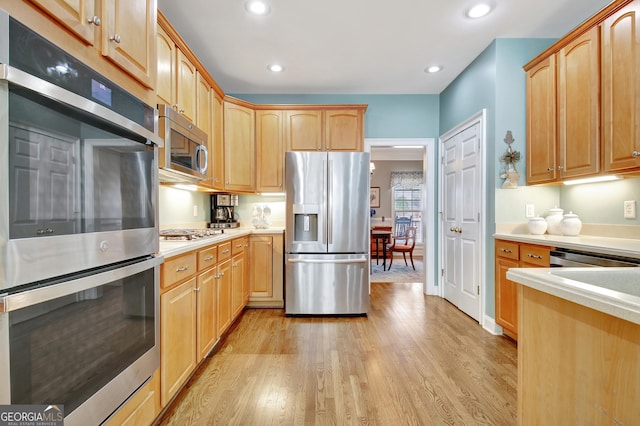 kitchen featuring light wood-style flooring, stainless steel appliances, light countertops, and recessed lighting